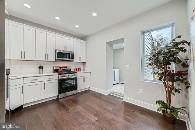 kitchen with washer / dryer, white cabinets, dark wood-type flooring, and appliances with stainless steel finishes