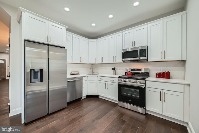 kitchen featuring dark wood-type flooring, sink, decorative backsplash, appliances with stainless steel finishes, and white cabinetry