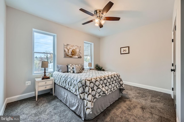 bedroom with multiple windows, dark carpet, and ceiling fan