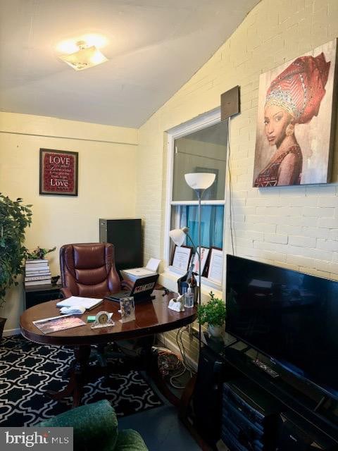 home office featuring brick wall and lofted ceiling