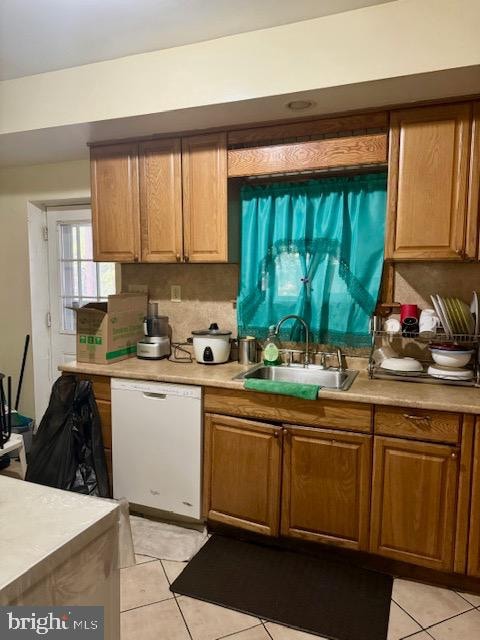 kitchen featuring light tile patterned flooring, decorative backsplash, white dishwasher, and sink