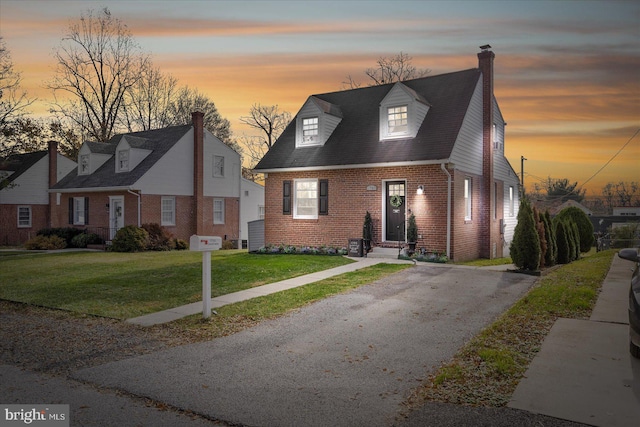 cape cod house featuring a yard