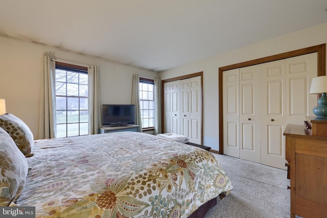 bedroom with multiple closets and light colored carpet