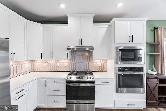 kitchen with decorative backsplash, appliances with stainless steel finishes, white cabinetry, and hardwood / wood-style floors