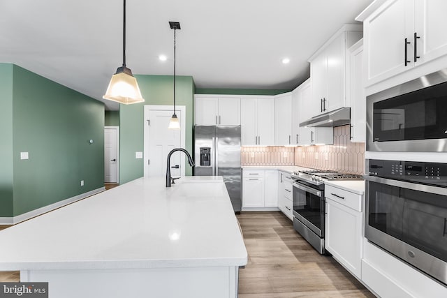 kitchen with a center island with sink, decorative light fixtures, white cabinets, and appliances with stainless steel finishes