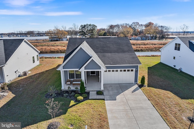 view of front of property featuring a water view, a front lawn, covered porch, and a garage