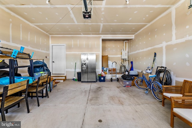 garage featuring stainless steel fridge with ice dispenser and a garage door opener