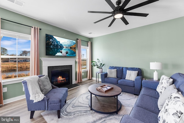 living room with plenty of natural light, ceiling fan, and light hardwood / wood-style flooring