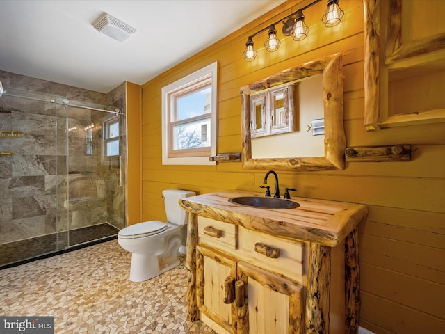 bathroom with vanity, toilet, an enclosed shower, and wooden walls