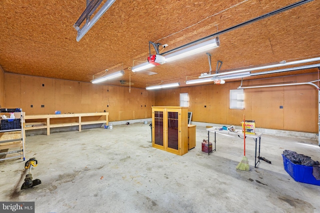 garage featuring a garage door opener and wooden walls