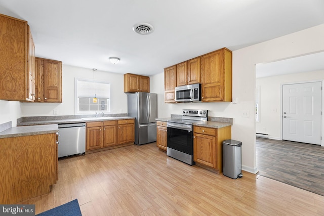 kitchen with appliances with stainless steel finishes, light wood-type flooring, a baseboard radiator, and sink