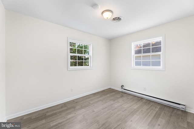 empty room featuring light wood-type flooring and baseboard heating