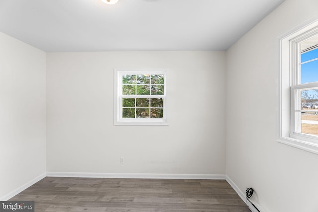 spare room featuring hardwood / wood-style flooring, baseboard heating, and a wealth of natural light