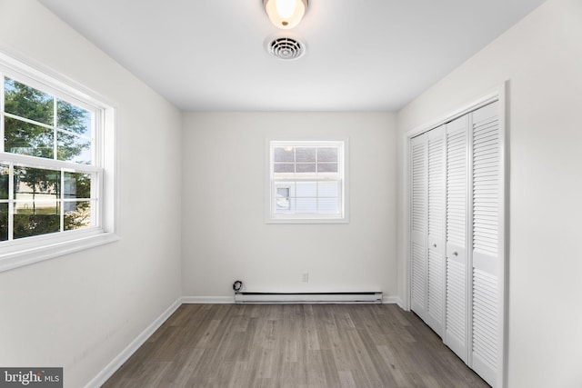 unfurnished bedroom featuring a closet, a baseboard radiator, and light wood-type flooring