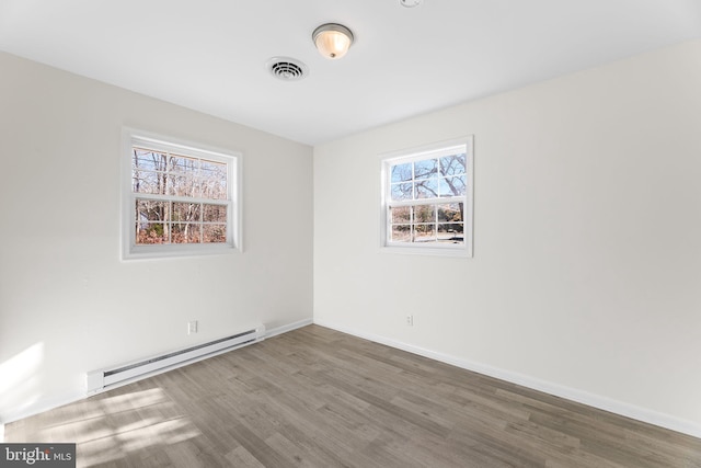 spare room featuring hardwood / wood-style flooring and a baseboard heating unit