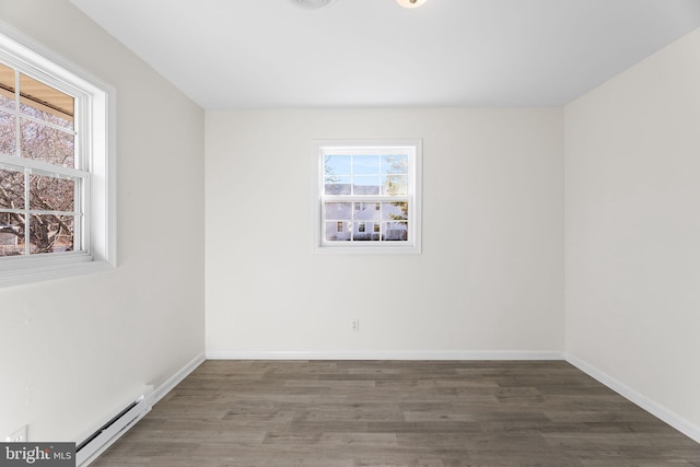 spare room with dark hardwood / wood-style floors, baseboard heating, and a healthy amount of sunlight