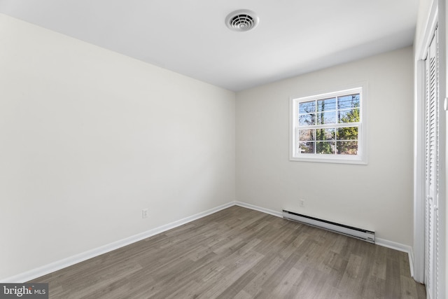 unfurnished bedroom featuring light hardwood / wood-style floors and a baseboard heating unit