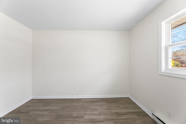 spare room featuring dark hardwood / wood-style flooring, baseboard heating, and a healthy amount of sunlight