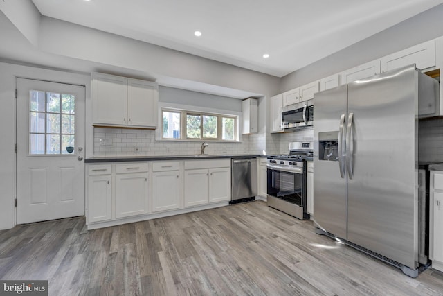 kitchen featuring a healthy amount of sunlight, decorative backsplash, white cabinetry, and stainless steel appliances