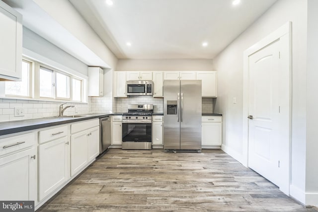 kitchen with white cabinets, light wood-type flooring, and stainless steel appliances