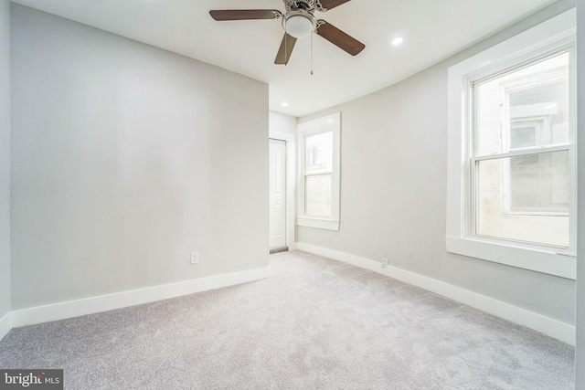 empty room featuring ceiling fan and light colored carpet