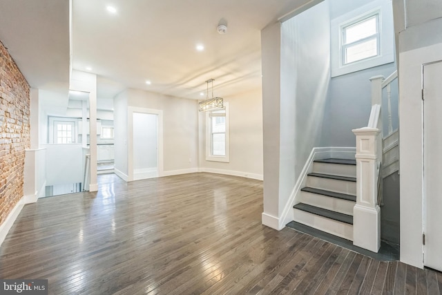 unfurnished living room with a wealth of natural light and dark wood-type flooring