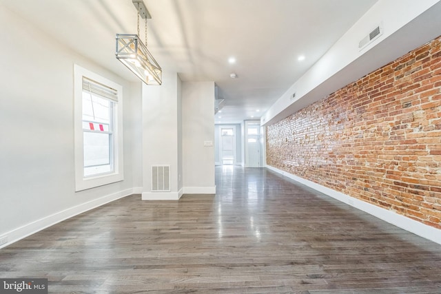 empty room with brick wall and dark hardwood / wood-style floors