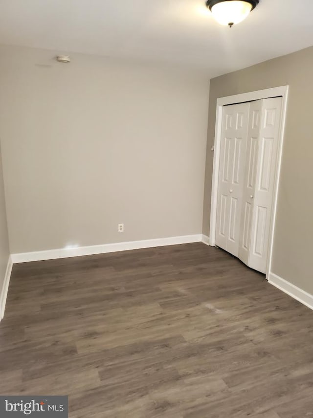 unfurnished bedroom featuring a closet and dark wood-type flooring