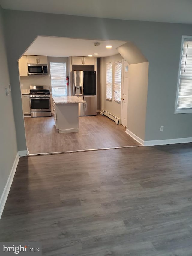 kitchen featuring hardwood / wood-style floors, stainless steel appliances, a baseboard radiator, and a healthy amount of sunlight