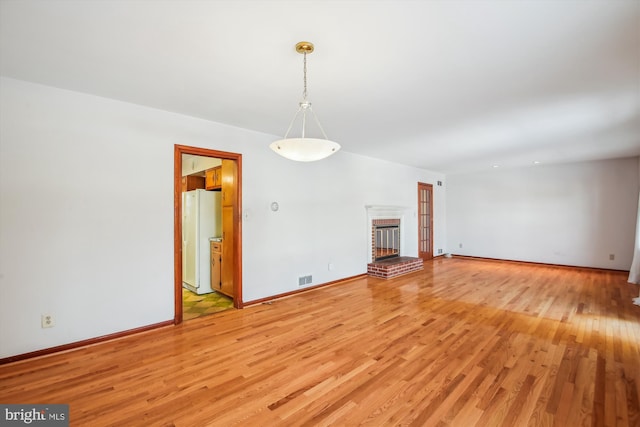 unfurnished living room with a brick fireplace and light hardwood / wood-style floors