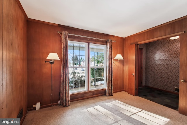 carpeted spare room featuring wood walls