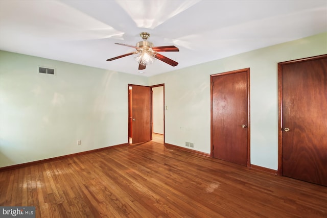 unfurnished bedroom with ceiling fan, wood-type flooring, and multiple closets