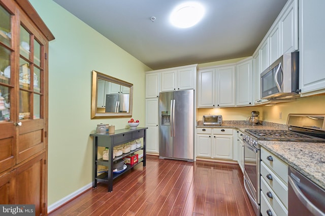 kitchen featuring white cabinets, light stone countertops, stainless steel appliances, and dark wood-type flooring