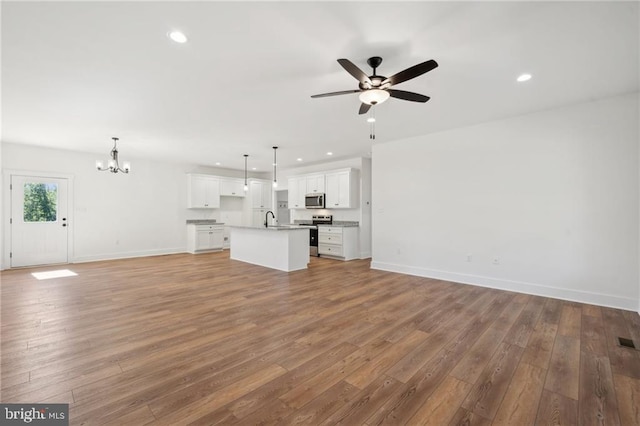 unfurnished living room with hardwood / wood-style floors, ceiling fan with notable chandelier, and sink