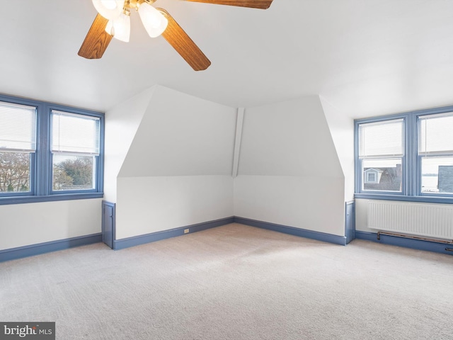 additional living space featuring ceiling fan, light carpet, radiator, and vaulted ceiling