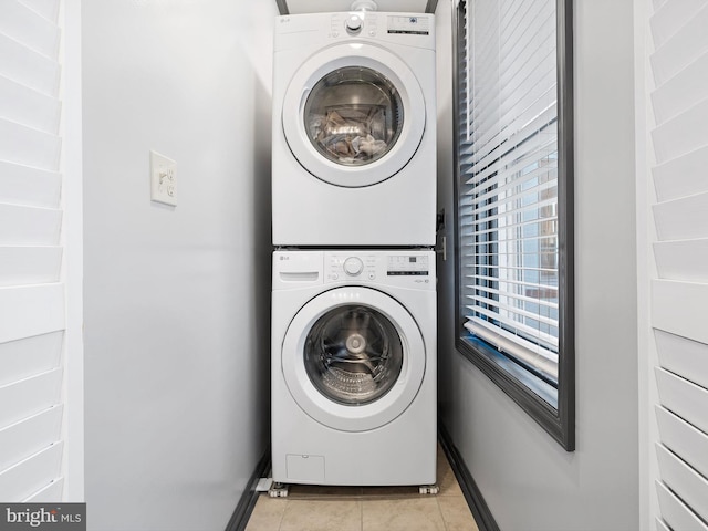 washroom featuring light tile patterned floors and stacked washing maching and dryer