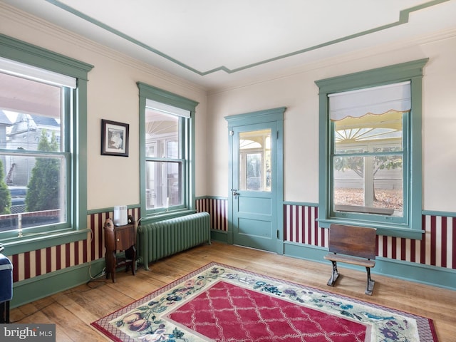 sitting room with radiator heating unit, hardwood / wood-style floors, and ornamental molding