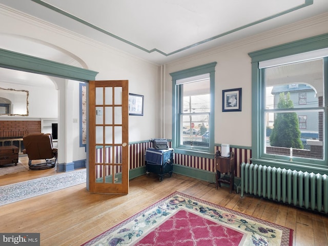 living area featuring wood-type flooring, radiator heating unit, and ornamental molding