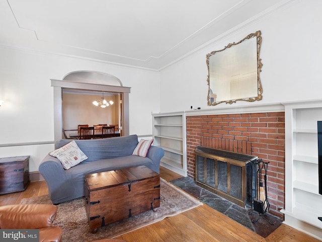 living room featuring a fireplace, hardwood / wood-style floors, an inviting chandelier, and ornamental molding