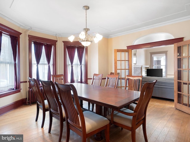 dining area with a healthy amount of sunlight, light hardwood / wood-style flooring, crown molding, and a notable chandelier