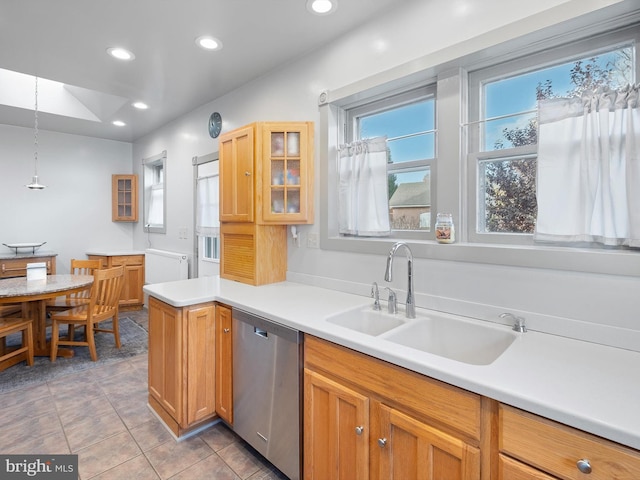 kitchen with kitchen peninsula, stainless steel dishwasher, sink, pendant lighting, and light tile patterned flooring