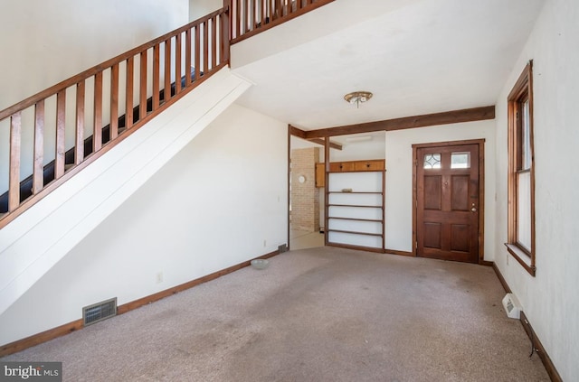 carpeted foyer entrance with beam ceiling