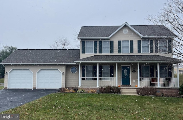 view of front of house with a porch, a garage, and a front lawn