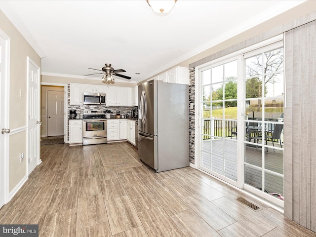 kitchen featuring white cabinetry, ornamental molding, tasteful backsplash, and stainless steel appliances