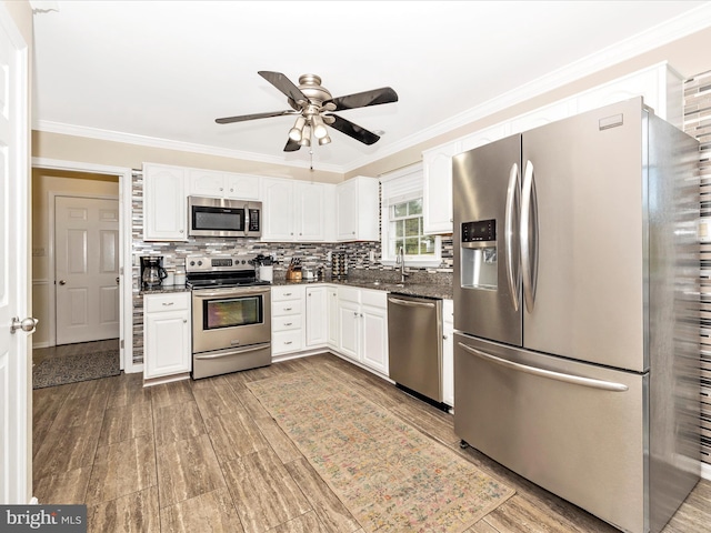 kitchen with tasteful backsplash, crown molding, appliances with stainless steel finishes, and white cabinets