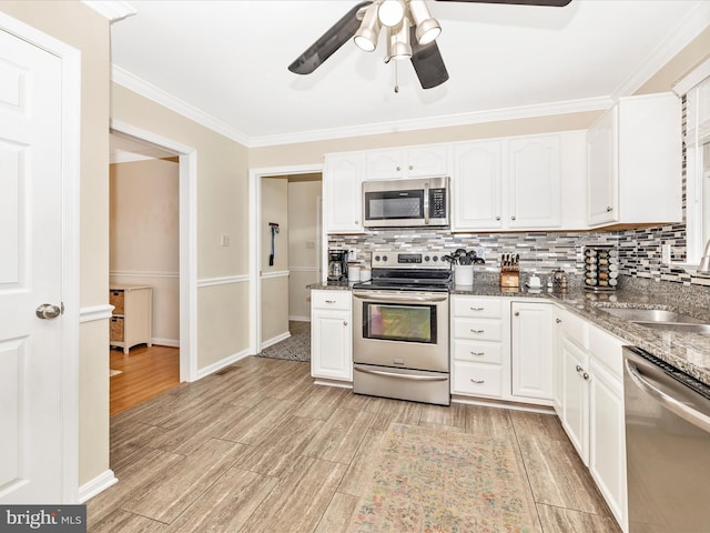 kitchen featuring appliances with stainless steel finishes, sink, dark stone countertops, and white cabinets