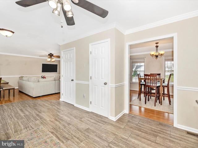 living room with crown molding and ceiling fan with notable chandelier