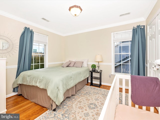 bedroom with ornamental molding and light hardwood / wood-style floors