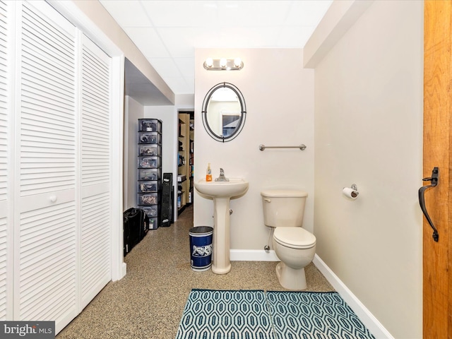 bathroom with a drop ceiling, sink, and toilet