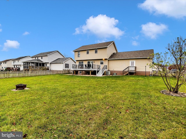 back of property with a deck, a fire pit, and a lawn